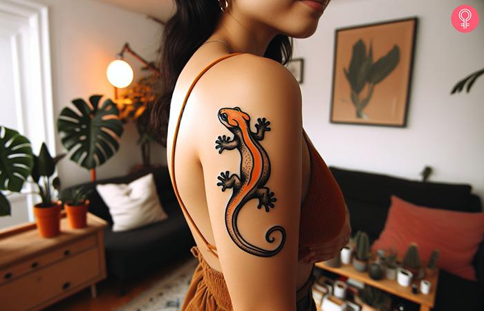A tattoo of an orange lizard on the arm of a woman