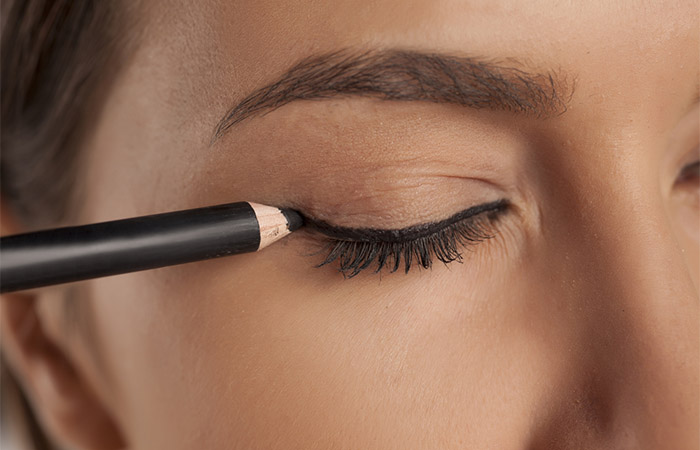 Woman applying a thick line of eyeliner after applying a thin line