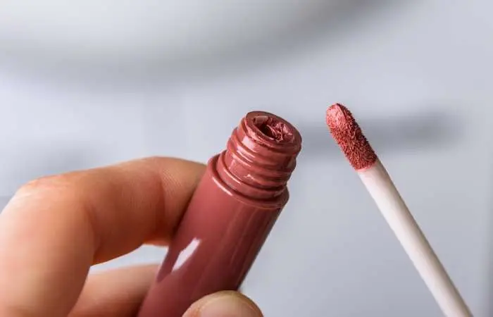 A woman holding liquid lipstick in her hands