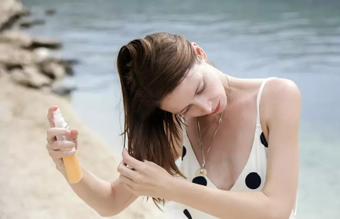 Woman spraying sunscreen on hair