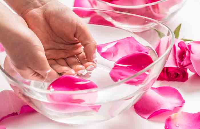 Woman soaking her hands in a bowl of rose water