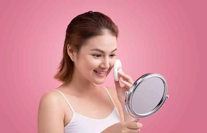 Woman cleaning face with toner using damp cotton pad