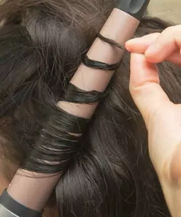 A woman using a wand to create curls