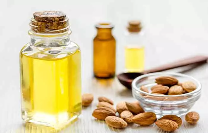 Bottles of almond oil and a bowl of almonds as a remedy to treat a dark neck
