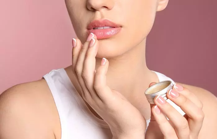 Woman applies lip balm to manage dry skin on her lips