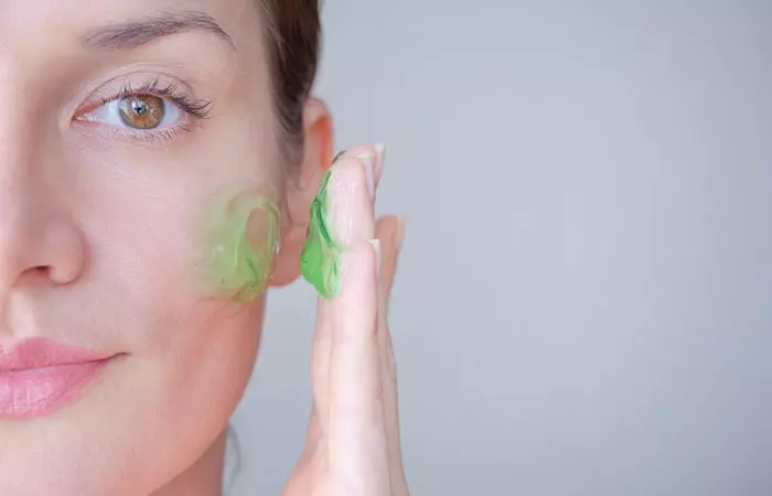 Woman applies aloe vera gel to her face to manage dry skin