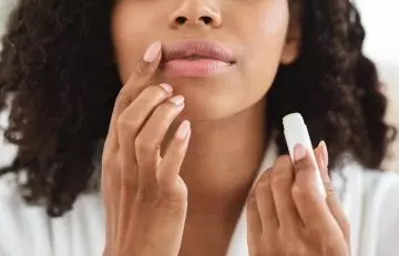 A woman moisturizing her lips with a lip balm