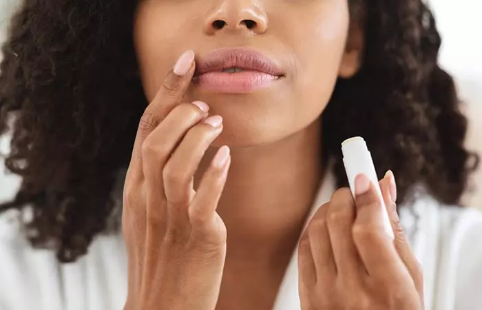 A woman moisturizing her lips with a lip balm