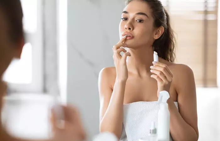 A woman applying lip balm to moisturize her lips