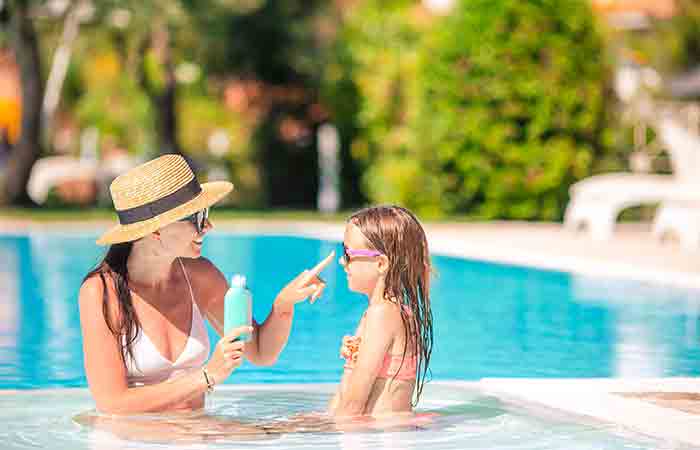 Woman applying waterproof sunscreen on her child in the pool