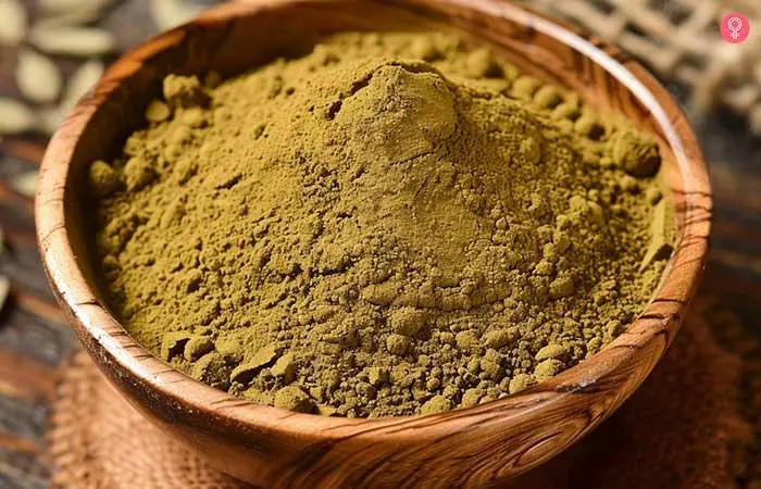 A wooden bowl filled with henna powder.