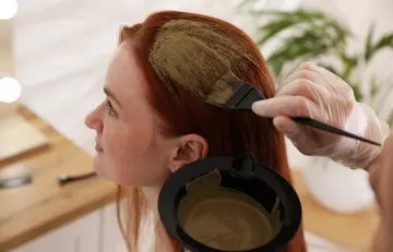 Young woman applying henna and banana hair pack for hair care