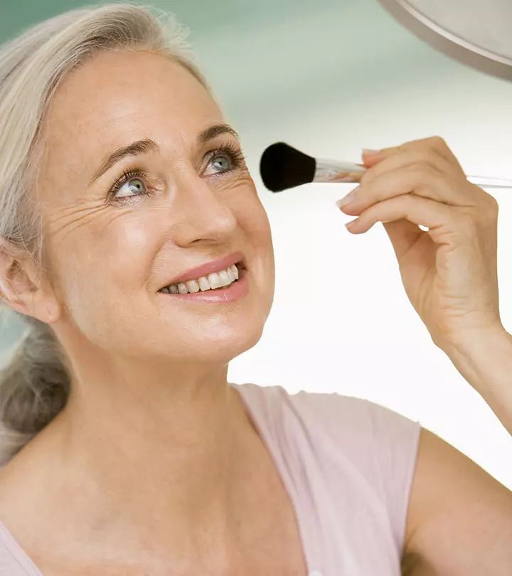 An older women applying makeup on her face