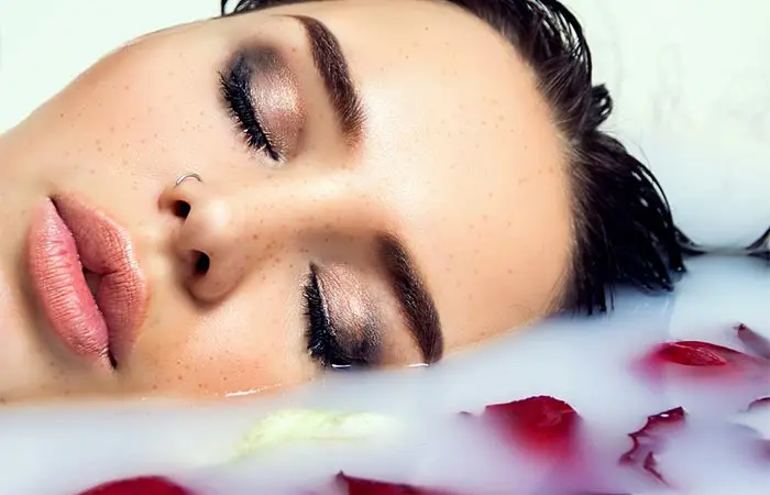 A woman taking a bath in milk and rose petals