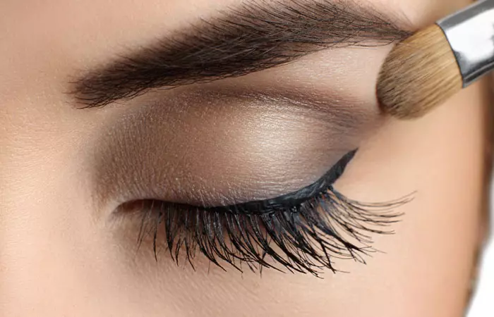 Woman applying eyeshadow to her droopy eyes