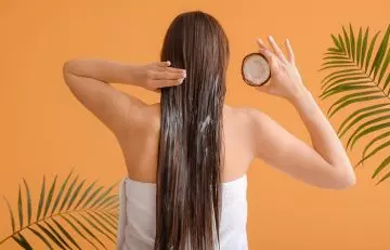Woman oiling her hair with coconut oil