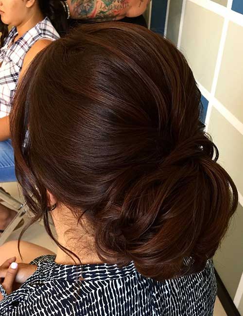 A low bun medium length hairstyle with side bangs