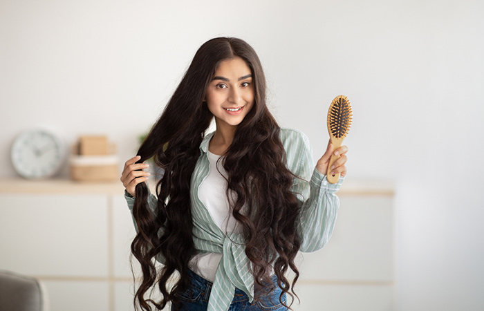 Woman holding a hairbrush with her hair showing no hair fall