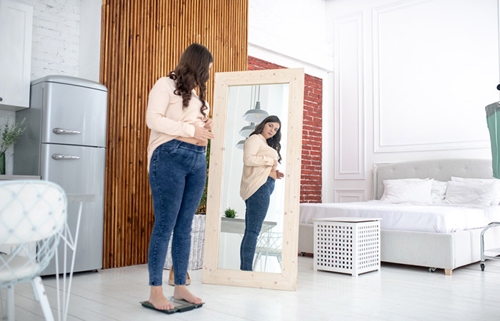 Woman checking her weight and looking in the mirror