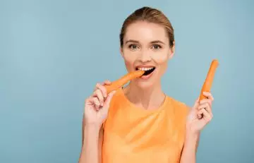 Woman eating carrots for naturally glowing skin