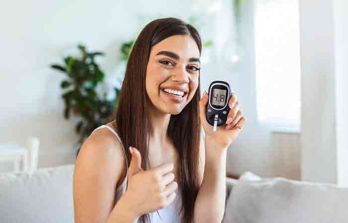 Woman holding a glucometer happy with the results