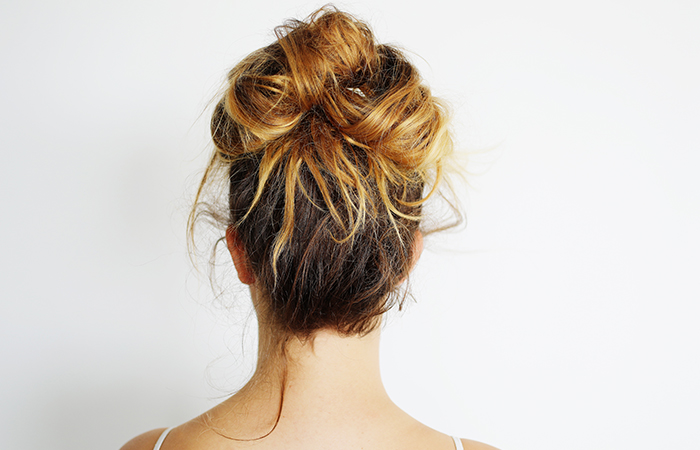 Trendy messy knot bun hairdo on highlighted hair