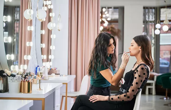 Woman getting lipstick applied by a professional makeup artist