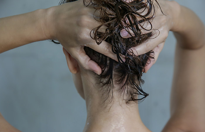 Back view of woman conditioning her hair constantly leading to greasy hair