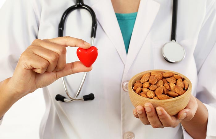 Doctor holding a heart shape in one hand and a bowl of almonds in the other