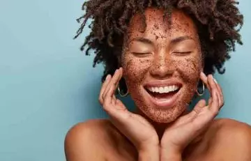 Woman smiling while exfoliating skin