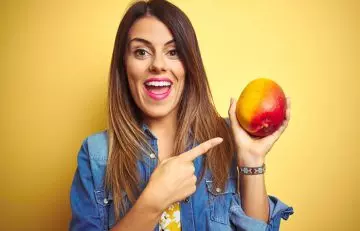 A happy woman holding a mango