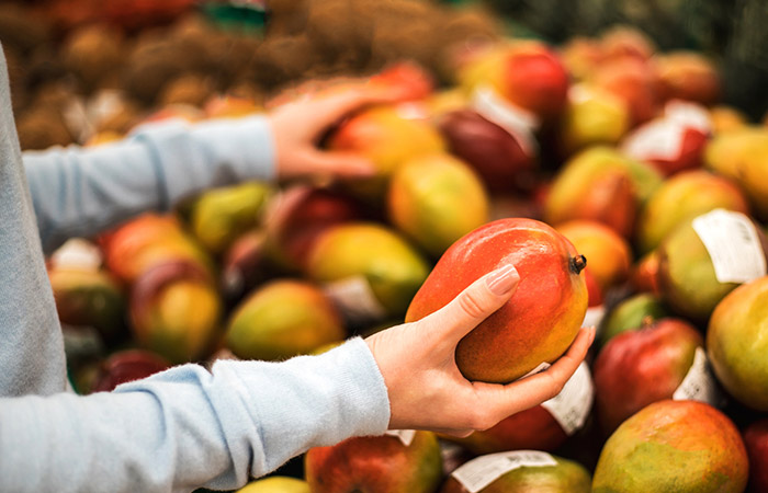 A woman picking fresh mangoes at the supermarket