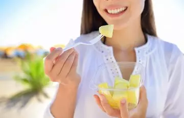 Woman eating pineapple to promote skin health