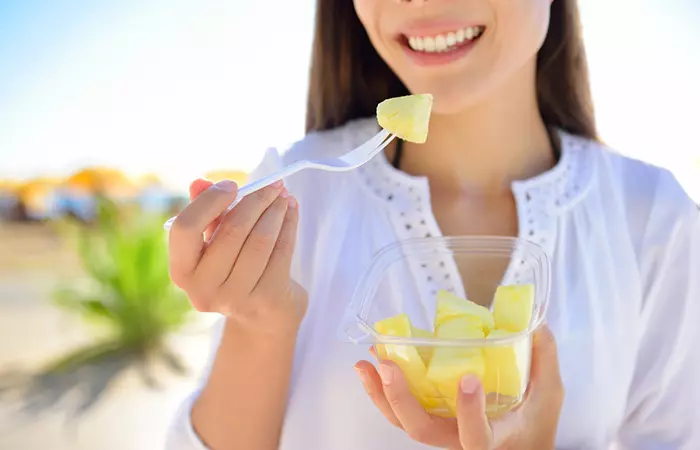 Woman eating pineapple to promote skin health