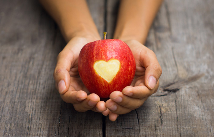 Hands holding an apple with a heart cutout