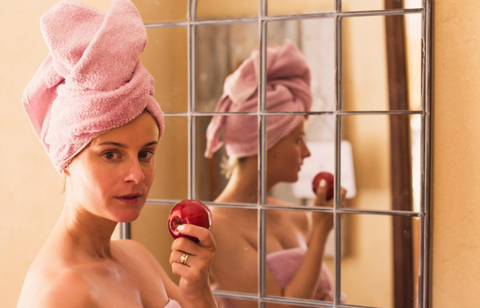 Woman in a towel eating an apple