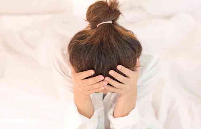 Woman resting her head into her hands due to stress which can be potentially managed with loquats