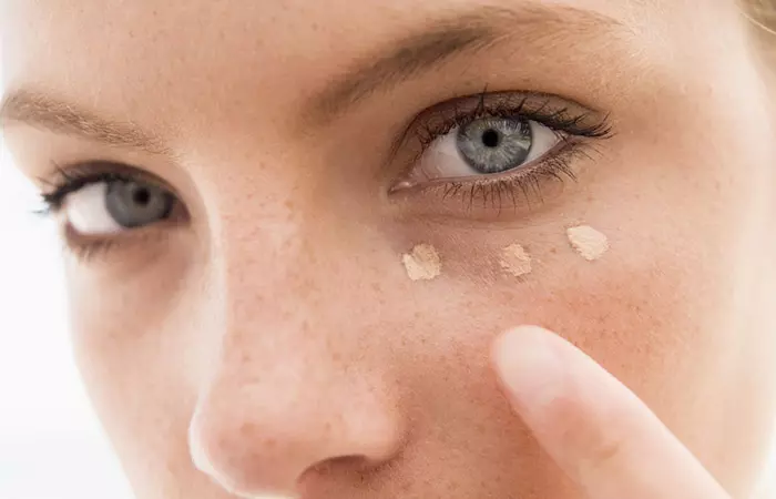 Closeup of woman using darker foundation as concealer