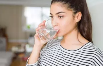 Woman drinking water to manage the side effects of GM diet
