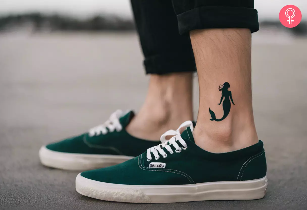 A black silhouette of a mermaid tattoo inked above the ankle bone