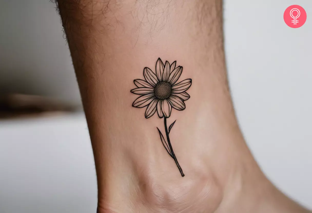 A minimalistic shaded daisy tattoo inked above the ankle bone