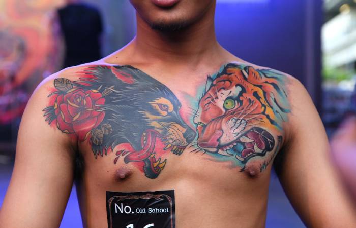 A neo-traditional wolf tattoo on a man’s chest