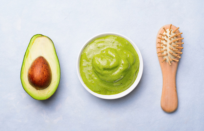 A spread of avocado hair mask and wooden brush for application