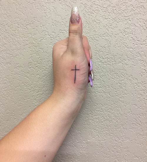 Cross tattoo on the thumb