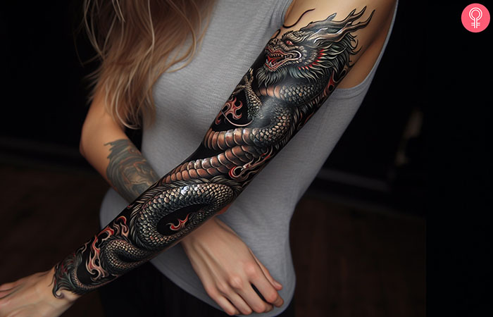 A woman with a black dragon sleeve tattoo.