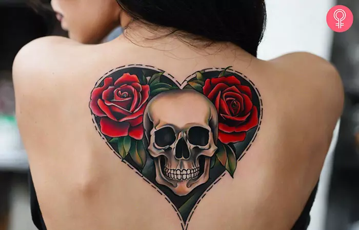 A woman showing a heart skull tattoo on her back