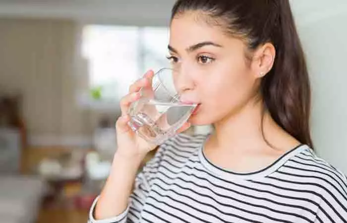 A woman drinking water to stay hydrated.