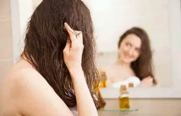 A woman oiling her hair.