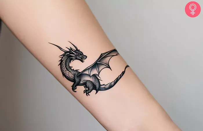 A woman with a small dragon tattoo on her forearm.