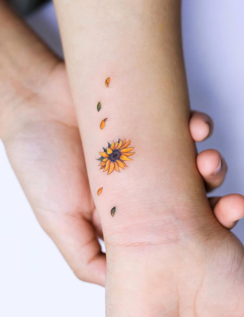 Colored minimalist sunflower tattoo on wrist